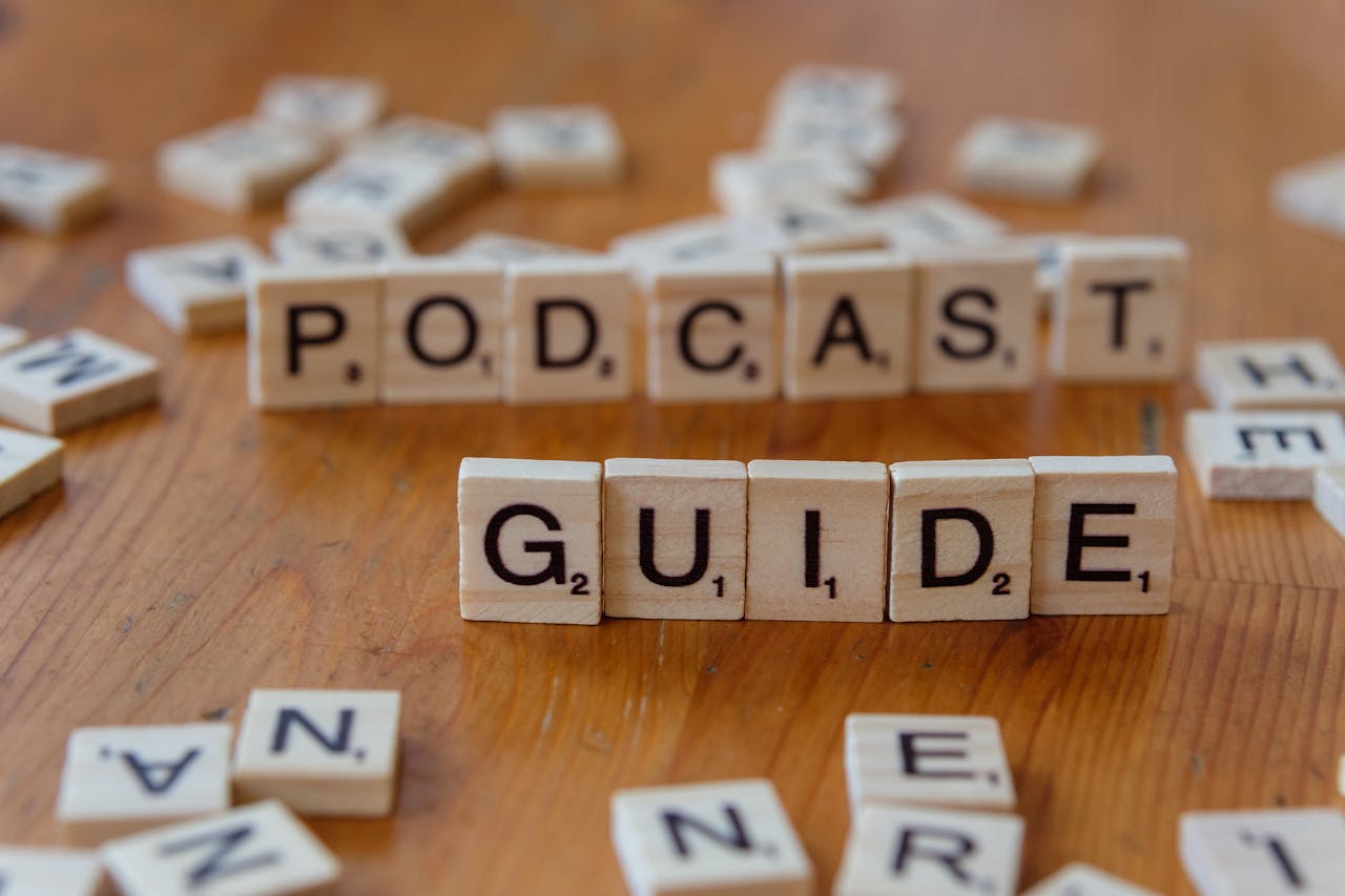 Scrabble tiles forming the words Podcast Guide on a wooden surface.